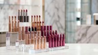 Luxury lipstick collection in clear acrylic organizer display with rose gold tubes and various shades from nude to deep berry tones for cosmetic branding.