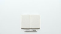 Open notebook with grid paper and pen on white background for planning, writing, sketching and creative work projects.