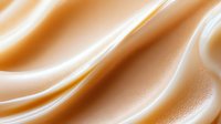 Luxurious golden silk fabric with flowing waves and soft highlights creating elegant textile background for fashion and interior design projects.