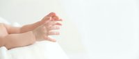 Newborn baby hands reaching up on soft white blanket against clean background for parenting and childcare concepts.
