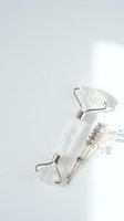 White jade facial roller with dried lavender flowers on clean minimalist background for skincare and wellness routines.