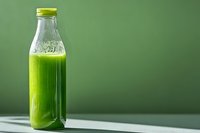 Fresh green smoothie in glass bottle with yellow cap on neutral background for healthy lifestyle and nutrition concepts.