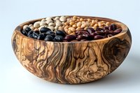 Assortment of dried legumes in rustic olive wood bowl with natural grain pattern, perfect for healthy cooking and nutrition concepts.