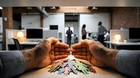 Businessman hands protecting diverse paper cutout people figures in modern office environment symbolizing employee care and corporate responsibility.
