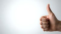 Human hand showing thumbs up gesture against clean white background expressing approval, success and positive feedback for business presentations.