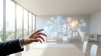 Businessman hand reaching toward glowing email and message icons floating in modern office with large windows overlooking cityscape, representing digital communication and business correspondence.