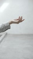 Woman's hand extended outward in open palm gesture wearing light linen sleeve against neutral background, conveying offering, acceptance, or mindfulness for wellness and lifestyle concepts.