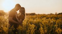 Romantic couple embracing in golden sunflower field during sunset, intimate moment in nature, love and relationship concept for wedding photography.