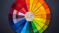 Vibrant color wheel showing spectrum of hues from red to blue arranged in circular segments against dark background, useful for design theory and color psychology.