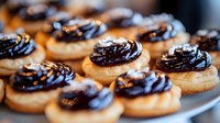 Freshly baked cookies with dark chocolate frosting swirls arranged on plate, close-up view showing rich texture and glossy topping. Sweet homemade dessert for cafe menu.