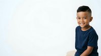 Young boy, approximately 6-8 years old, Hispanic ethnicity, wearing dark blue t-shirt, smiling at camera with happy expression against white background. Isolated portrait suitable for educational materials, family websites, and children's content.