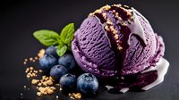 Purple blueberry ice cream scoops with fresh berries, mint leaves and crunchy granola topping on dark background, drizzled with berry sauce.