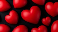 Red glossy hearts scattered on black background creating romantic pattern for Valentine's Day cards, wedding invitations and love declarations.