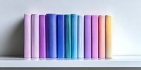Colorful hardcover books arranged in rainbow spectrum order standing on white shelf against light wall, creating minimal modern home library display.