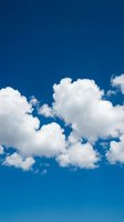 Fluffy white cumulus clouds floating against vibrant deep blue sky on clear sunny day for nature backgrounds and weather concepts.