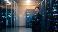 Professional Asian woman IT specialist standing confidently in modern data center server room with arms crossed, technology infrastructure background.