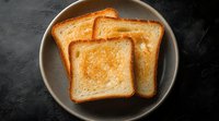 Freshly toasted bread slices with golden-brown surface served on gray ceramic plate against dark background, top view food photography for menu or cookbook.