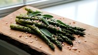 Fresh green asparagus spears seasoned with herbs and spices on wooden cutting board, ready for healthy cooking and gourmet meal preparation.