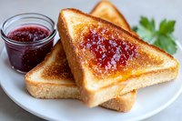 Golden toasted bread slices with strawberry jam spread and glass jar on white plate, breakfast meal ready to serve with fresh parsley garnish.