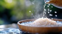 Raw white rice grains in ceramic bowl with water drops and steam, dramatic lighting against dark background. Fresh cooking ingredients concept.