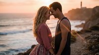Romantic couple embracing at sunset on rocky coastline with lighthouse, golden hour ocean waves creating intimate moment for love and relationship concepts.