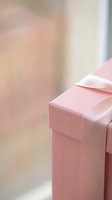 Pink gift box with satin ribbon bow on soft blurred background for celebrations, holidays, birthdays, anniversaries and special occasions.