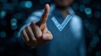 Caucasian businessman touching glowing blue checkmark hologram on dark background with bokeh lights, representing digital approval and verification.