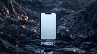 Modern smartphone with blank white screen standing on dark rocky surface outdoors for mockup and app presentation purposes.