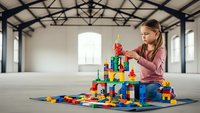Young girl with long brown hair building colorful block tower in spacious industrial loft with exposed beams. Creative play and construction concept.