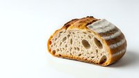 Artisan sourdough bread slice showing airy crumb structure and golden crust on white background, perfect for bakery marketing and food photography.