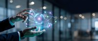 Businessman hands holding glowing atomic structure hologram with orbiting electrons in modern office environment representing science and technology innovation.
