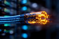 Glowing fiber optic cable transmitting digital data with orange light effect and blue technology background, modern network communication concept.
