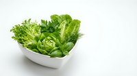Fresh green lettuce and mixed salad leaves in white bowl on white background, healthy eating and nutrition.