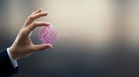 Businessman hand holding pink transparent cube with maze pattern inside representing problem solving and strategic thinking in corporate environment.