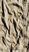 Wrinkled beige cotton fabric with metal snap buttons and stitching details, showing natural creases and folds from wear and use for textile backgrounds.