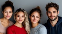 Diverse group of young adults smiling at camera against gray background, showing genuine happiness and friendship. Professional portrait for business or lifestyle content.