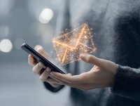 Hands holding smartphone with glowing digital envelope hologram emerging from screen representing email communication and mobile messaging technology.