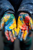 Colorful paint-covered palms showing vibrant yellow, blue, red and green paint smears against dark background, representing creativity and artistic expression.