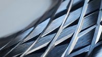 Close-up of metallic mesh or grille with diagonal woven pattern, featuring shiny silver and dark blue tones, suitable for industrial, automotive, or technology backgrounds.