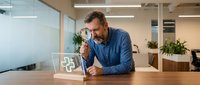 Middle-aged Caucasian businessman examining documents with magnifying glass in modern office workspace for detailed analysis and investigation work.
