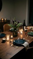 Elegant dinner table setting with dark blue plates, lit candles, fresh floral arrangement, wine bottle and bread for fine dining event planning and hospitality design.