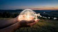 Glowing light bulb held in hand against sunset landscape, symbolizing innovation, ideas, and sustainable energy solutions for business and environmental concepts.