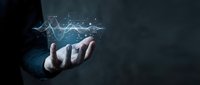 Businessman hand holding glowing digital wave graph with data visualization on dark background for financial analysis and business growth concepts.