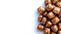 Chocolate covered marshmallow candy cubes arranged on white background, sweet dessert pattern with copy space for text, isolated confectionery.
