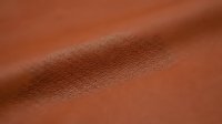 Close-up of cognac leather texture with natural grain and subtle highlights, suitable for fashion, upholstery, and design projects.