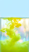 Vibrant green ink or paint dissolving in clear water creating abstract fluid patterns and swirls in glass container against soft blue background.