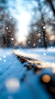 Magical winter scene with falling snowflakes and bokeh lights creating dreamy atmosphere. Ground level view of snow covered surface with soft focus background.