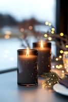 Warm glowing candles with golden fairy lights create cozy winter atmosphere on table. Holiday home decor with soft bokeh background for seasonal celebrations.