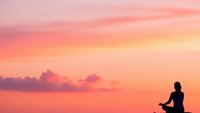 Silhouette of person meditating at sunset with pink orange sky clouds peaceful zen mindfulness relaxation spiritual wellness yoga practice serenity.