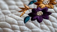 Colorful embroidered flowers with purple petals and golden centers on white quilted fabric background. Traditional needlework craft design for home decor projects.